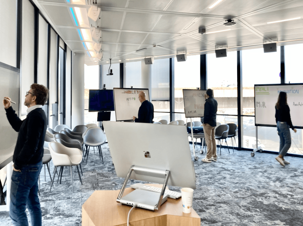 Salle de travail en haut d'un gratte siècle ou des personnes travaillent sur des tableaux numériques génats.